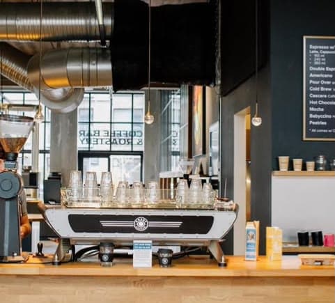 Espressomaskinen på baren og menutavlen bag — ROAST Coffee